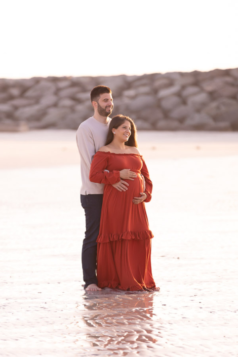 Maternity photo of an expecting couple and their child at Al Khan Beach in Sharjah, all standing together by the water during a family maternity photoshoot