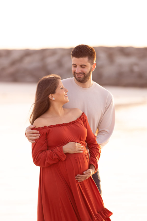Pregnant woman standing on Sunset Beach in Dubai during a maternity photoshoot, with the Burj Al Arab visible in the background