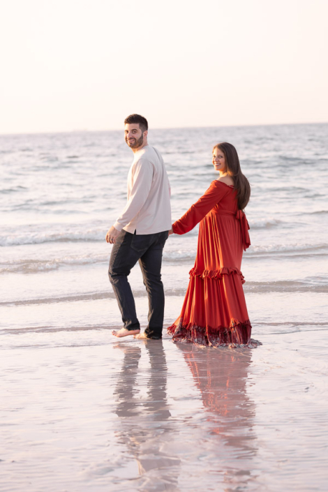 Maternity photo of an expecting mother and father with their young child on Jumeirah Beach in Dubai, all holding the baby bump together