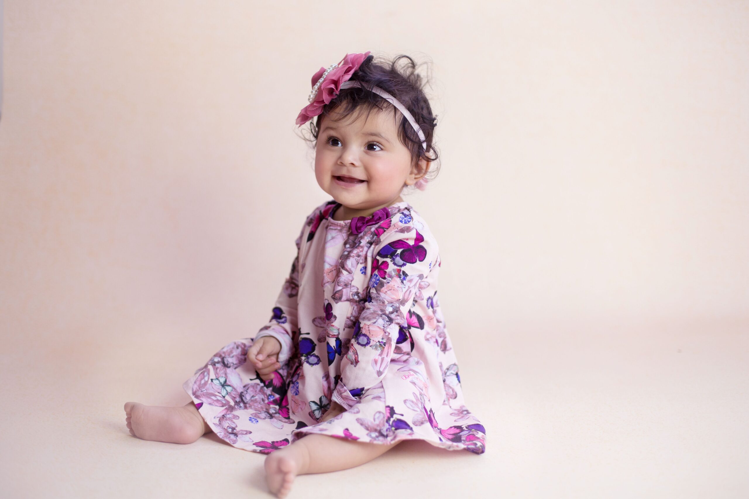 Smiling baby girl in floral dress during baby photography in Dubai
