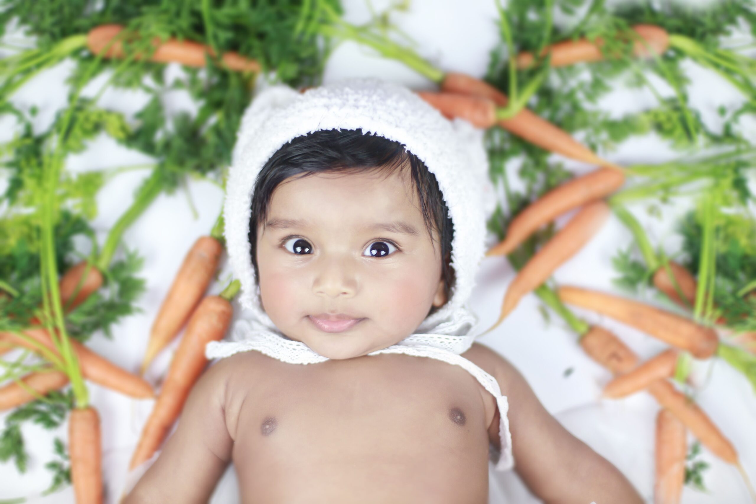 Baby lying among carrots during a creative baby photoshoot in Dubai
