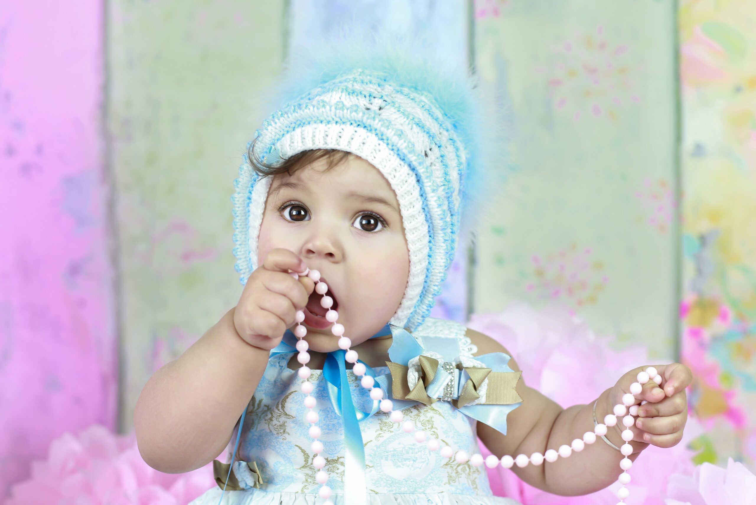 Baby in a blue knit chewing beads during a baby photography shoot in Dubai