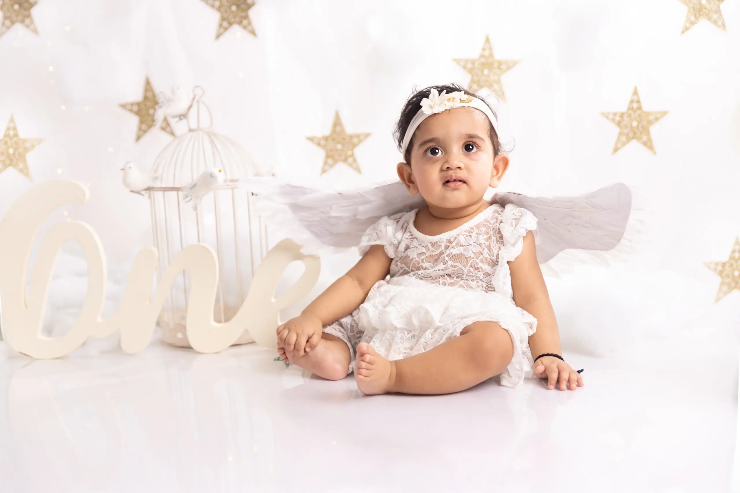 Baby girl in white dress with angel wings during baby photography in Dubai