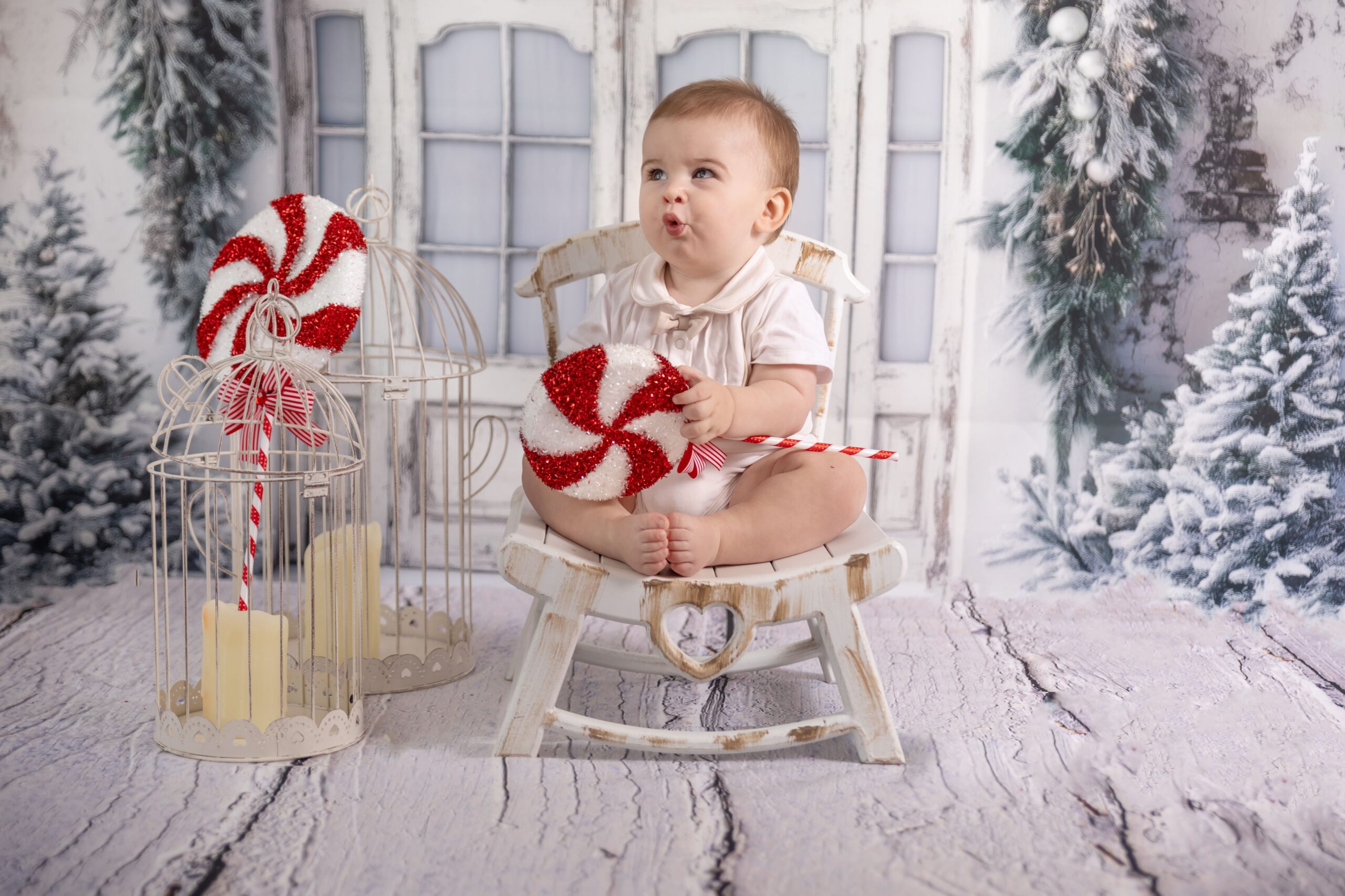 Baby boy holding a candy prop in a Christmas baby photography session in Dubai