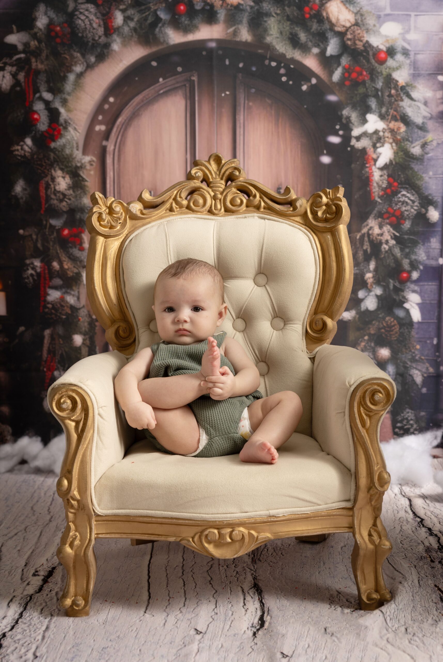 Baby seated on a gold chair during a newborn photoshoot in Dubai