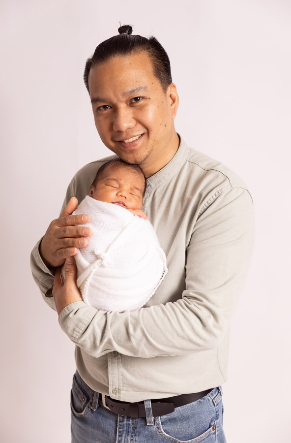 Father holding newborn baby during newborn photography in Dubai